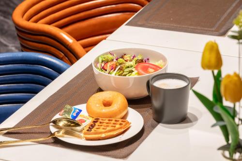 a table with a plate of food and a salad and a cup of coffee at Echarm PLUS International Hotel Zhujiang New Town Wuyangcun Metro Station Branch- Free Deliver Service to Canton Fair Complex During Canton Fair Period in Guangzhou