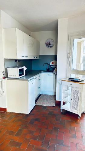 une petite cuisine avec des armoires blanches et un micro-ondes dans l'établissement Studio Saint-Cyprien Port, à Saint-Cyprien