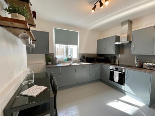 a kitchen with gray cabinets and a black table at Large 5 bed 3 bath house 300 meters from beach and restaurants in Newquay