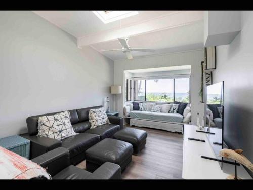 a living room with a couch and a tv at SeaRoos by the Seashore Beach Cottage in Durras