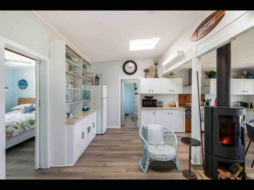 ein Zimmer mit einem Schlafzimmer und einer Küche mit Kamin in der Unterkunft SeaRoos by the Seashore Beach Cottage in Durras