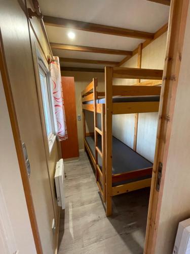 Cette petite chambre comprend 2 lits superposés et une porte. dans l'établissement Camping le Convivial Cottage climatisé 6-8 personnes, à Saint-Martial-de-Nabirat