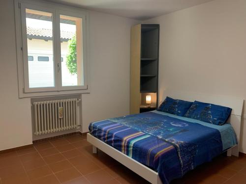 een slaapkamer met een bed met blauwe lakens en een raam bij Mo&Ma Home in Imola