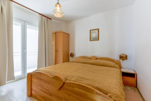 a bedroom with a wooden bed in a room with a window at Villa Fontana in Starigrad-Paklenica