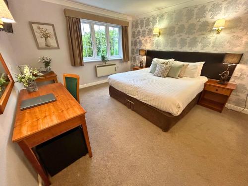 a bedroom with a bed and a desk with a laptop at New Forest Lodge in Landford