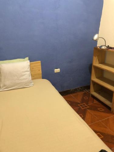 Cama en habitación con pared azul en Hospedaje el Jaguar Pacífico, en Antigua Guatemala