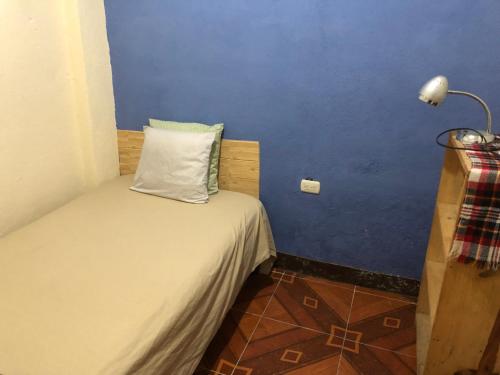 ein kleines Schlafzimmer mit einem Bett mit blauer Wand in der Unterkunft Hospedaje el Jaguar Pacífico in Antigua Guatemala