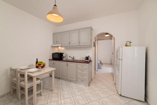 een keuken met een tafel en een witte koelkast bij Evangelia cozy apartment in Agios Nikolaos