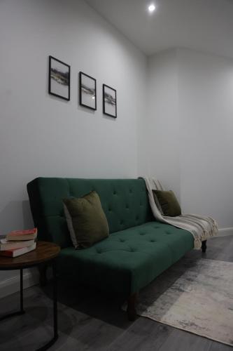 a green couch in a living room with a table at Modern and Comfy in City Centre PS4 , Free On Street Parking ,Walking Distance To Bus, Train Stations And Shopping Centres in Leicester