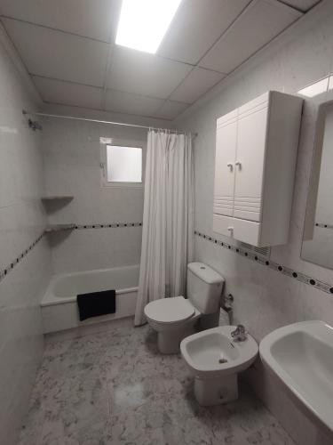 a white bathroom with a toilet and a sink at Sandy Home - Élvezd a tengerpartot! in La Mata