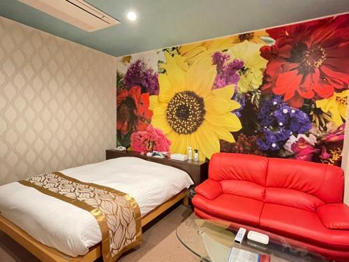 ホテル レディ في Kōtōdaitōri: غرفة نوم بسرير واريكة وجدارية زهرة
