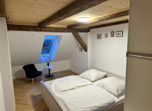 Un pequeño dormitorio con una cama y una silla. en Exklusive Maisonetten Wohnung mit Gartenzugang, en Augsburg