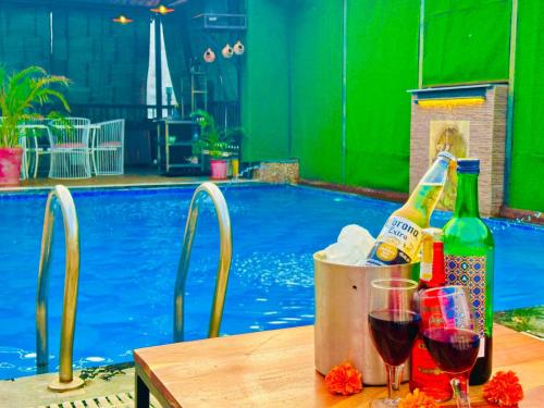 Hotel The Casa Hamilton, City Centre Amritsar في أمريتسار: طاولة مع زجاجات النبيذ والاكواب بجوار حمام السباحة