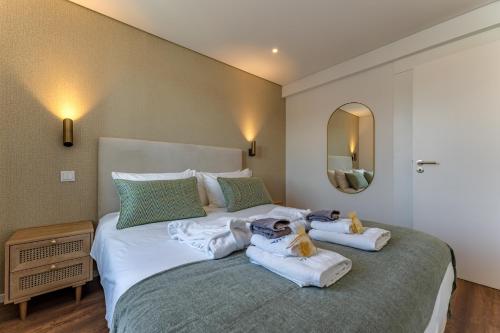een slaapkamer met een groot bed en handdoeken bij Douro View Charming Apartment Duplex in Valbom