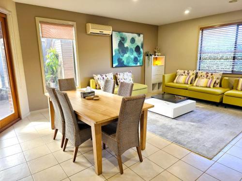 拉弗顿Specious ex-display 5 BDR house,up to 15 guests- Williams Landing的客厅里有一张桌子和一张黄色沙发
