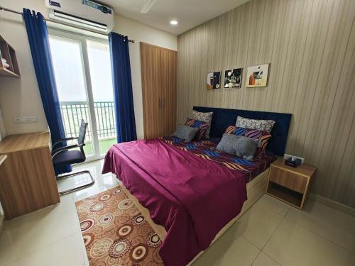 a bedroom with a bed with purple sheets and a window at Sandal suite by Mulberry Homestays in Noida