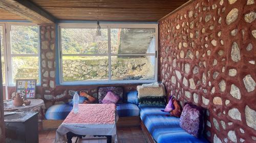 Habitación con sofá azul contra una pared de piedra. en Gîte Détape Affaska, en Izilane