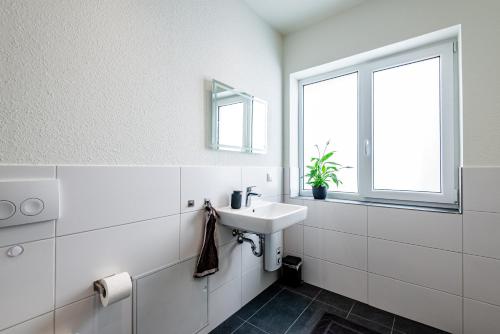 a white bathroom with a sink and a window at Wohnen im ehemaligen Schießstand in Cologne
