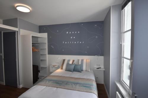 1 dormitorio con 1 cama con pared azul en Hotel Atlantique, en Le Palais