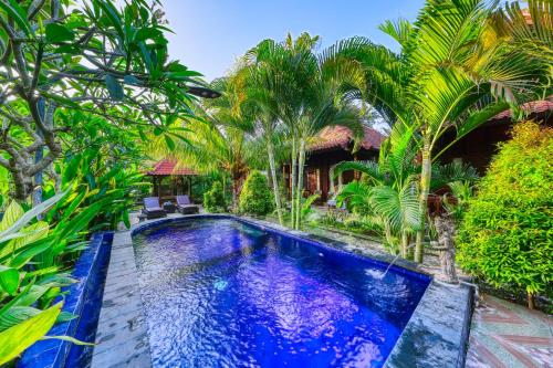 a swimming pool in front of a house with palm trees at Asoka Bungalows in Nusa Penida