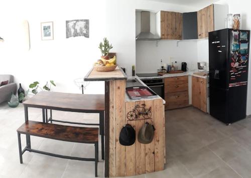 uma cozinha com uma mesa de madeira e um frigorífico preto em Charmante maison de vacances en Luberon em Beaumettes