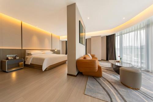 um quarto de hotel com uma cama e uma cadeira em Jiangshan Yunfan Sports Resort Hotel em Jiangshan