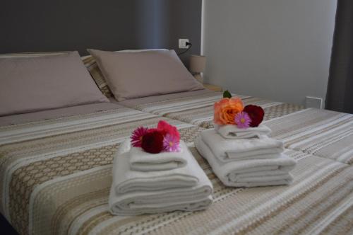 two towels with flowers on top of a bed at PALM House Affitta camere in Tortolì