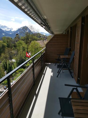 a balcony with a table and chairs and mountains at Hotel Brienzersee in Ringgenberg