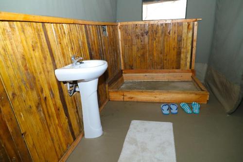 a bathroom with a sink and a wooden wall at Emunyan maasai Mara camp in Sekenani