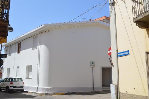 a white building with a large door on the side at PALM House Affitta camere in Tortolì