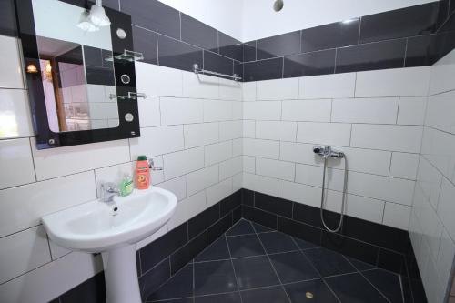 a black and white bathroom with a sink and a shower at Guri Guesthouse in Gjirokastër