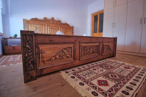 a large wooden bed in a room with a rug at Guri Guesthouse in Gjirokastër