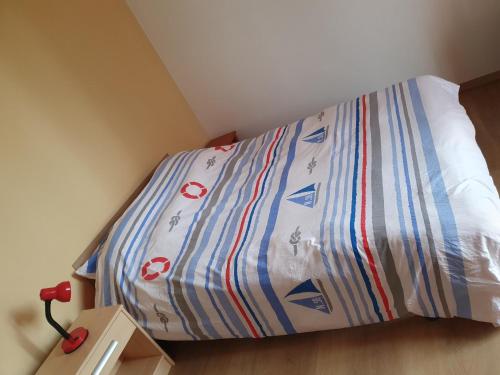 - un lit avec une couette bleue et blanche dans l'établissement Location les Bruyères, à Saint-Germain-sur-Ay