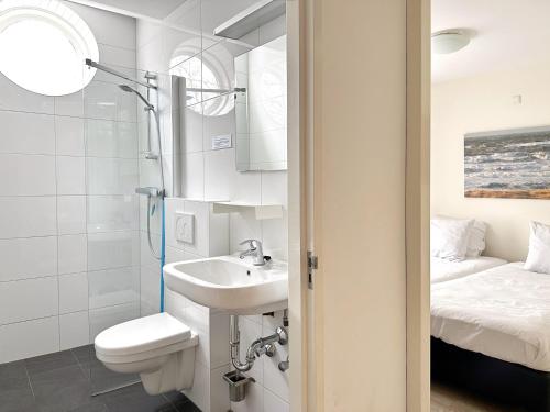 a bathroom with a sink and a toilet and a bed at Huis van Egmond aan Zee in Egmond aan Zee