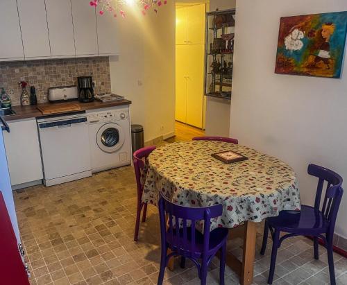a kitchen with a table with purple chairs and a washing machine at Superb apartment in the Marais in Paris