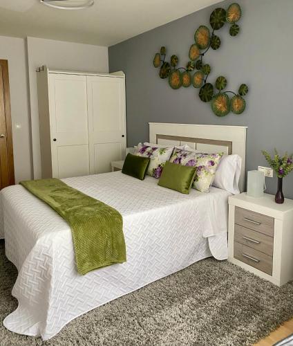 a bedroom with a large white bed with green pillows at APARTAMENTO CASA PLAYA in Boiro