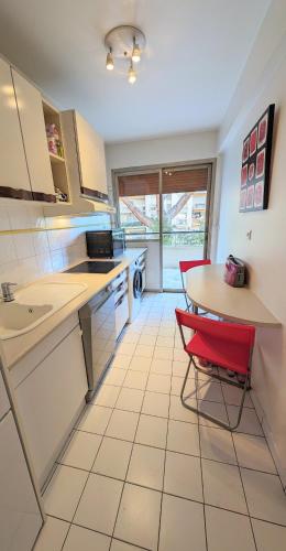 une cuisine avec une table et une chaise rouge dans l'établissement LACOUR7 Palmes dProperties, à Cannes