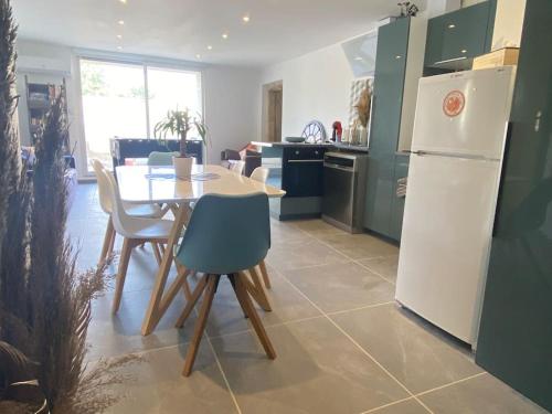 une cuisine avec une table et un réfrigérateur blanc dans l'établissement REZ de jardin moderne 4 chambres 8 personnes jardinet, à Bagnols-sur-Cèze