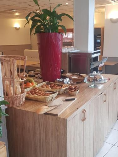 a table with food on it with a potted plant on it at KYRIAD ORANGE Centre Ville - HOTEL & RESTAURANT & BAR - La Galerie d'Art des Princes - Provence Alpes Côte d'Azur - France - Proche A7-A9 - exit21- Châteauneuf-du-Pape Avignon Bollene Nimes - 24h-24h in Orange