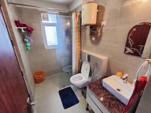 a bathroom with a toilet and a sink and a shower at Sandal suite by Mulberry Homestays in Noida