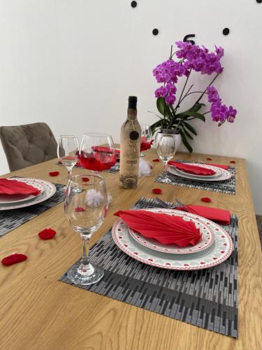 a wooden table with glasses of wine and flowers at Apartman Pranić Mostar in Mostar
