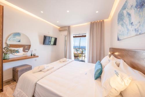 a bedroom with a large white bed and a window at Galatia Studios and Apartments in Benitses