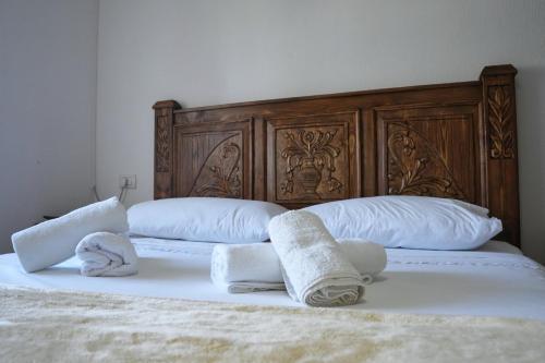 two towels on a bed with a wooden headboard at Guri Guesthouse in Gjirokastër