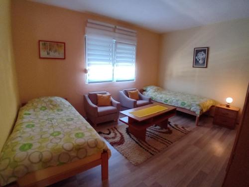 a room with two beds and a chair and a table at Smeštaj Vesna in Bajina Bašta