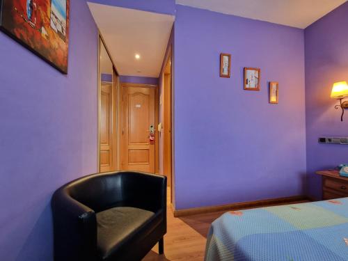 a bedroom with purple walls and a black chair at Hotel Virginia R.H. in Vinuesa