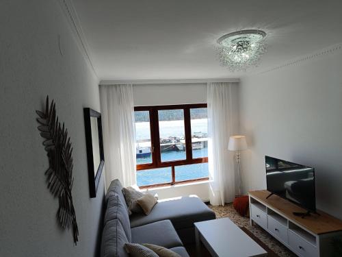 a living room with a couch and a window at Piso Frente al Mar, O Barqueiro 2 in O Barqueiro