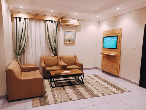 Alhamra Park hotel في جدة: غرفة معيشة مع كرسيين وتلفزيون