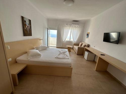 a bedroom with a bed and a couch and a television at Dima Vista in Dhërmi