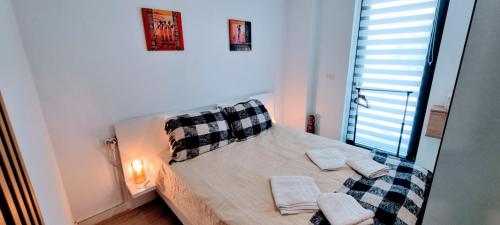 ein Schlafzimmer mit einem Bett mit Kissen und einem Fenster in der Unterkunft ATENEO - Studio DeLuxe Modern Apartment, Big Balcony, Plus Parking in Timişoara