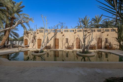 a building with trees and a pool of water at Olive Garden House Siwa in Siwa